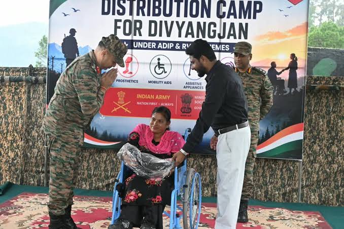 Indian Army officer greets a woman receiving a wheelchair at an artificial limb distribution camp for Divyangjan
